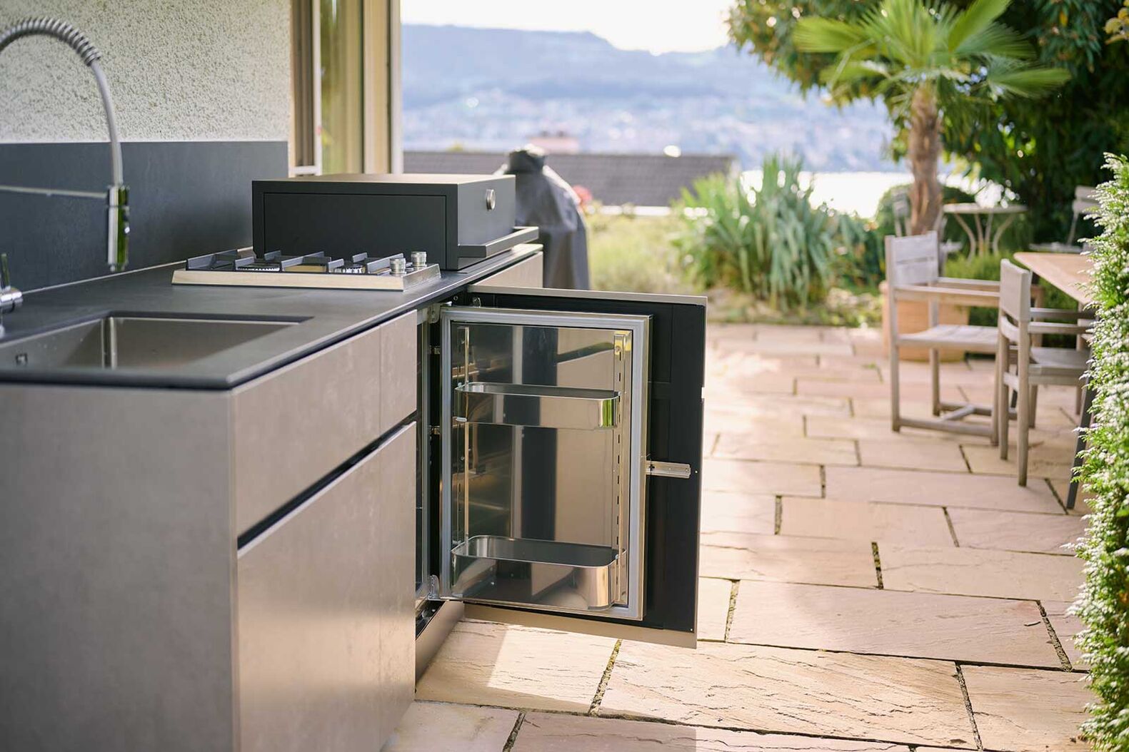 Die «Theiss Avers»-Outdoorküche mit integriertem Kochfeld und Laminam-Keramikoberflächen wärmt Grillgut an geselligen Sonnenabenden. Lynx Group GmbH, www.theiss.design