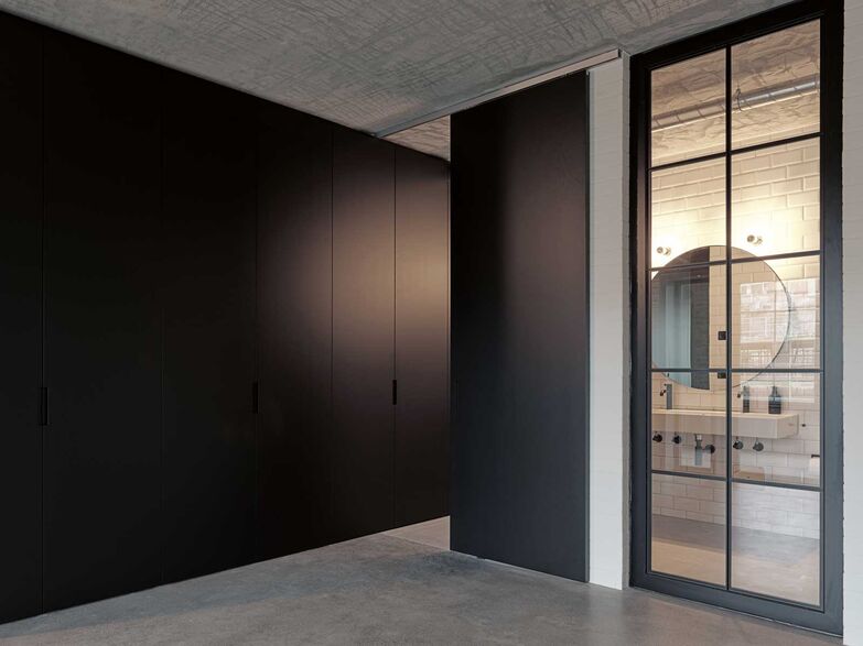 In der Ruhe liegt die Kraft: Ein minimalistisches Design wirkt automatisch ordentlicher. In dieser Loftwohnung in Cham wurden die Schränke und die Schiebetür perfekt aufeinander abgestimmt und mit demselben matten Lack behandelt. Innenausbauer Stuber Team hat mit den monochromen Schränken und der passenden Tür viel Stauraum geschaffen, der fast unsichtbar ist. www.stuberteam.ch