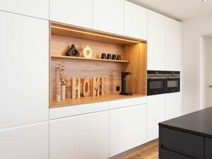 In der weissen Hochschrankfront mit Vorratsschrank, Kühlschrank und den beiden Geräteschränken mit Backofen/Steamer und Backofen/Mikrowelle wird die Kaffeenische mit der integrierten Beleuchtung zum Blickpunkt. Loosli AG.